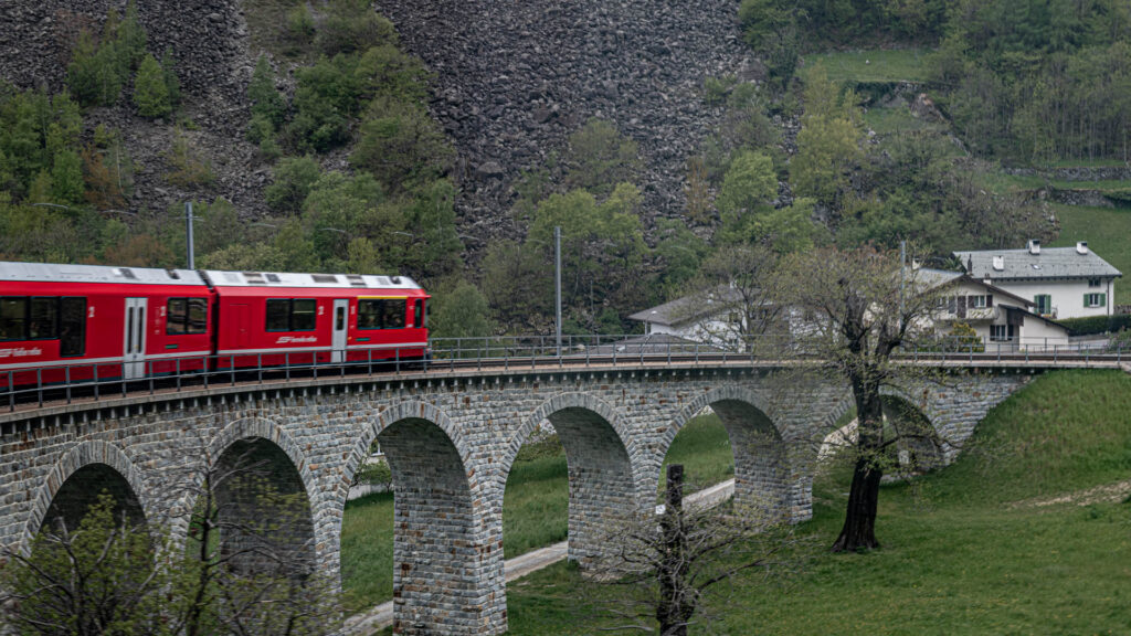 The Bernina Express passing through the mountain village of Pontresina on route to Tirano, Italy